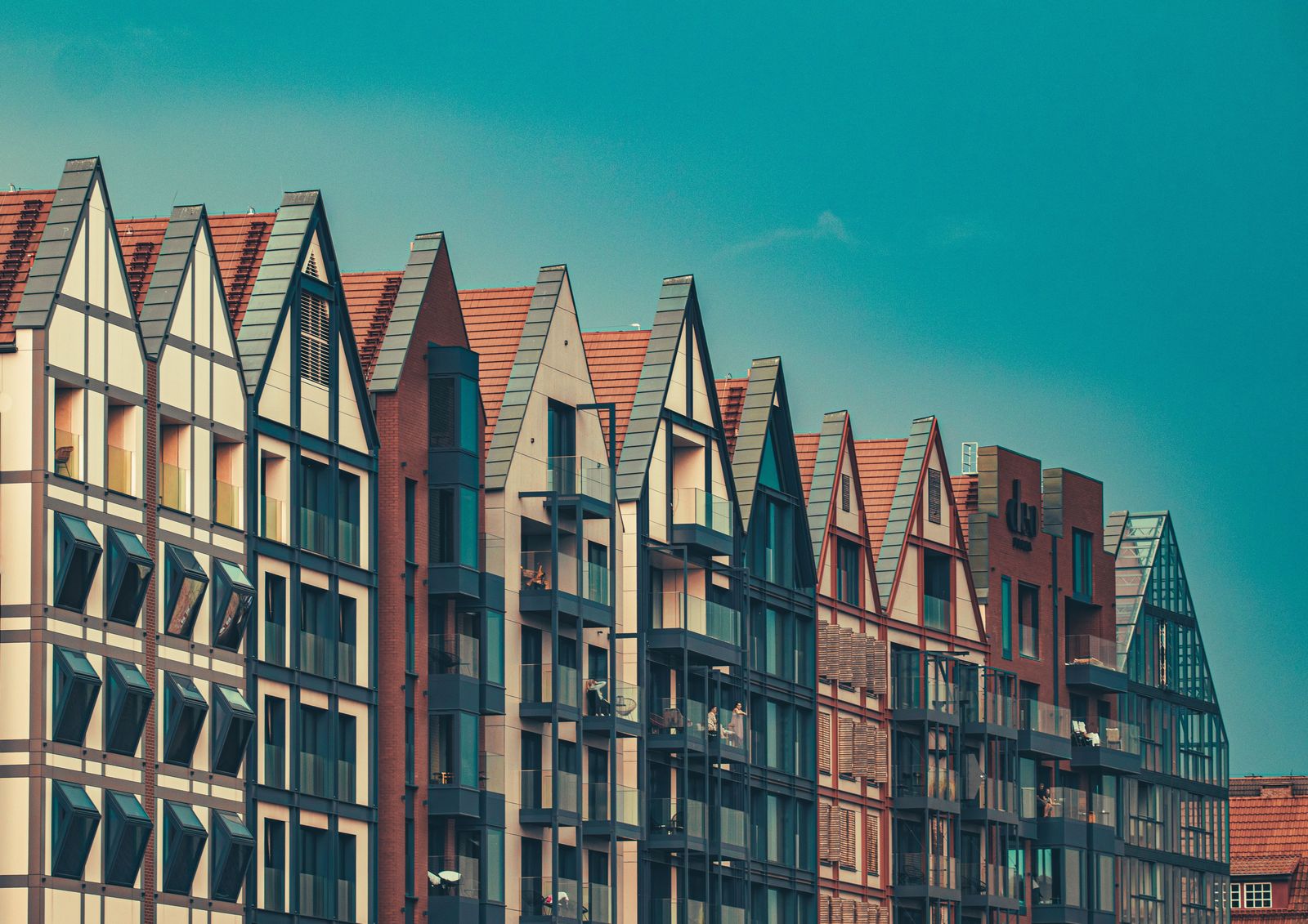 Terrace of gabled brick apartment buildings against a clear sky