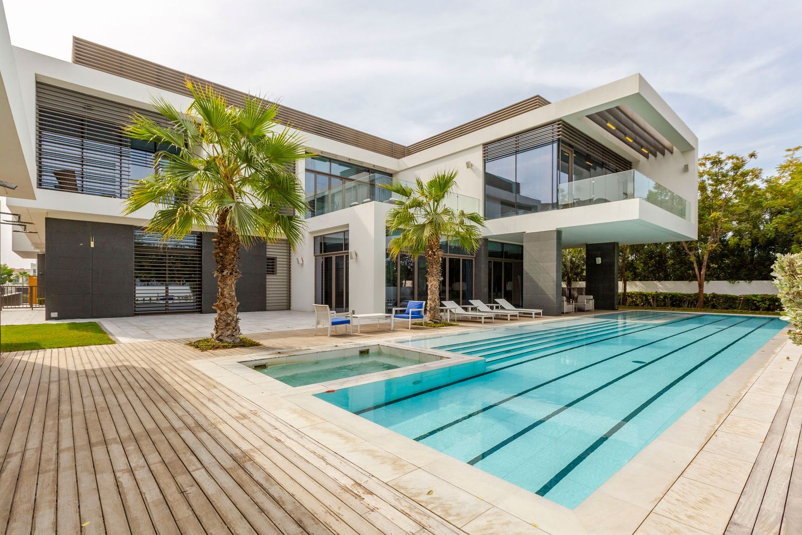 Modern white villa with an infinity pool framed by palm trees at golden hour