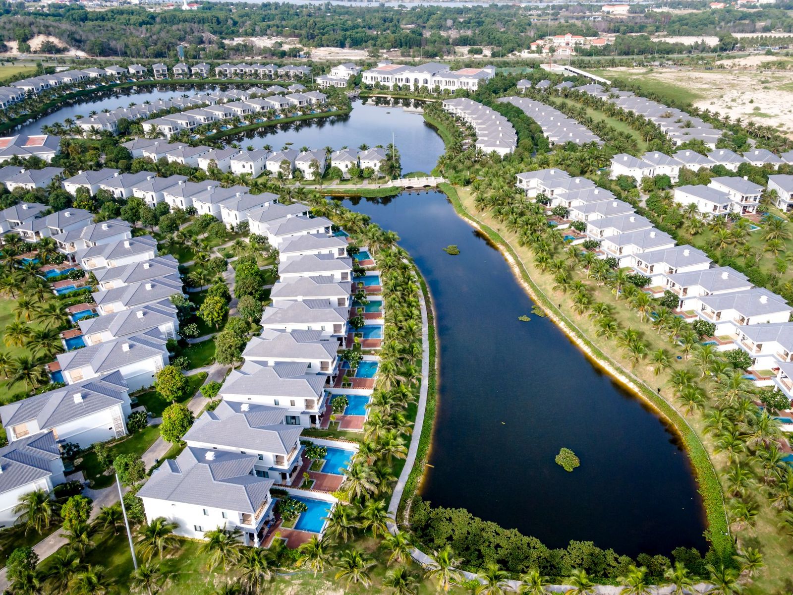 Aerial view of a crescent of white villas beside a lake