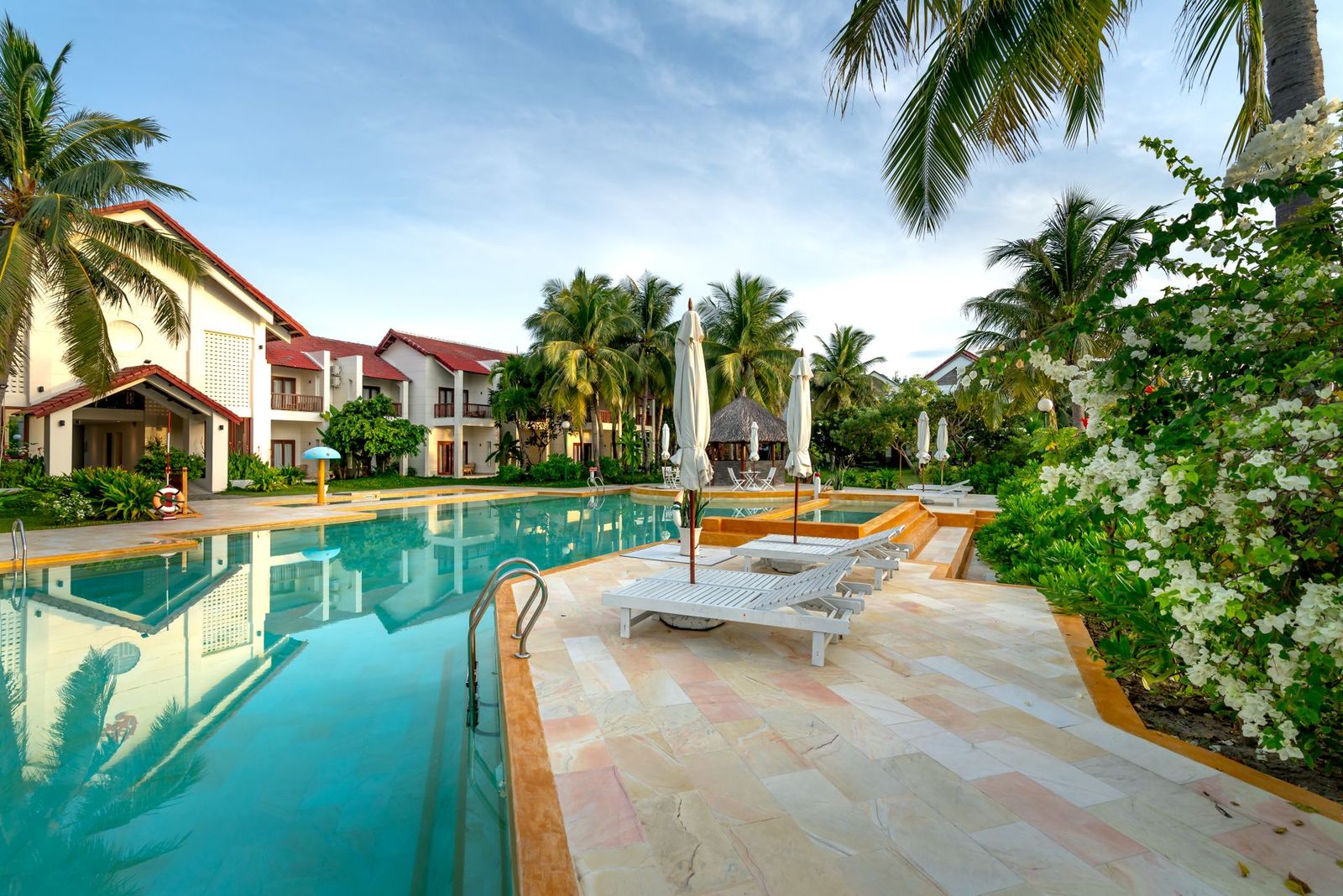 Turquoise pool surrounded by palms and flowering shrubs