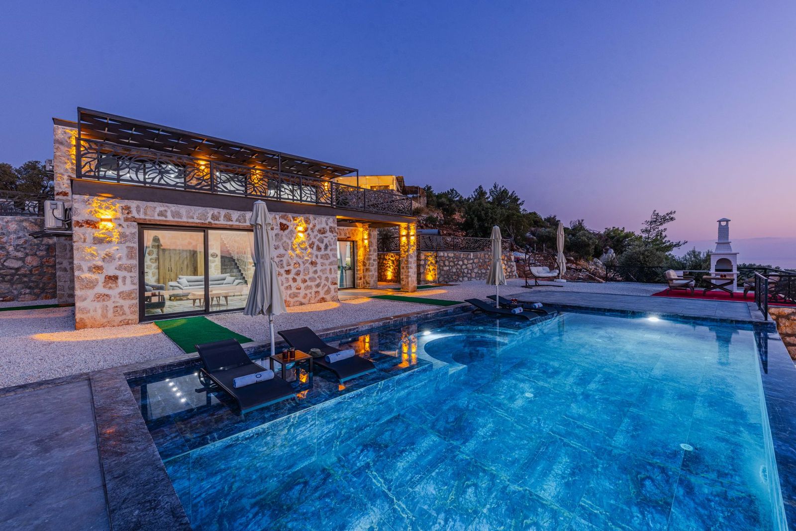 Natural stone villa with a pool lit at dusk