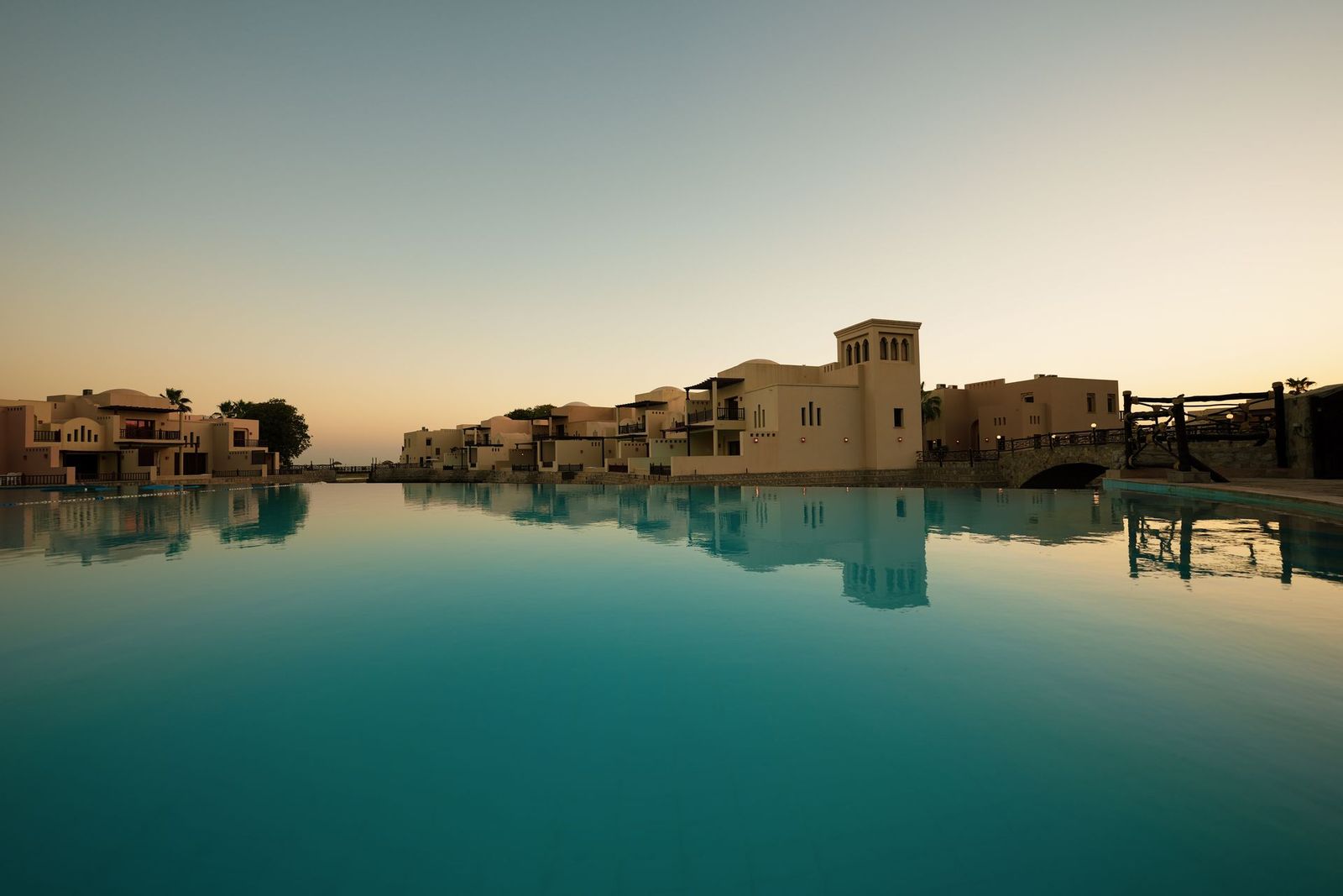Row of waterfront villas reflected in still water at sunset